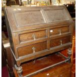 A 1920s geometric moulded oak slope front two-drawer writing bureau (some losses to mouldings),