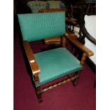 An early 20th century oak and green fabric studded upholstered pad back and seat open elbow chair,