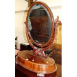 A large Victorian mahogany oval swing dressing mirror, raised on turned ribbon effect support, on