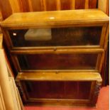 A 1930s moulded oak bookcase, having three glazed hinged doors and of lower stepped form, w.90cm