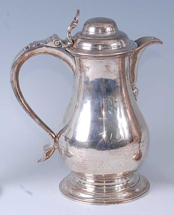 An early George III silver wine or beer jug, having a hinged domed cover, S-scroll handle, and