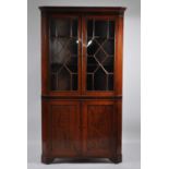 A late Georgian oak freestanding corner cabinet, having inlaid mahogany frieze over twin astragal