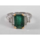 An 18ct white gold, emerald and diamond five stone ring, featuring a centre step cut emerald in a