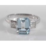 A white metal, aquamarine and diamond three stone ring, comprising a centre rectangular cut