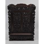 An early 20th century Chinese heavily carved and pierced hardwood side cabinet, the raised top