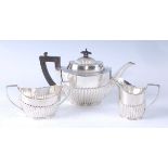 An Edwardian silver three-piece tea service, comprising teapot with ebonised handle and finial,