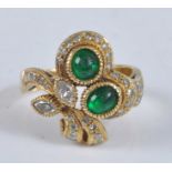 A yellow metal, emerald and diamond asymmetrical cluster ring, set with two cabochon green