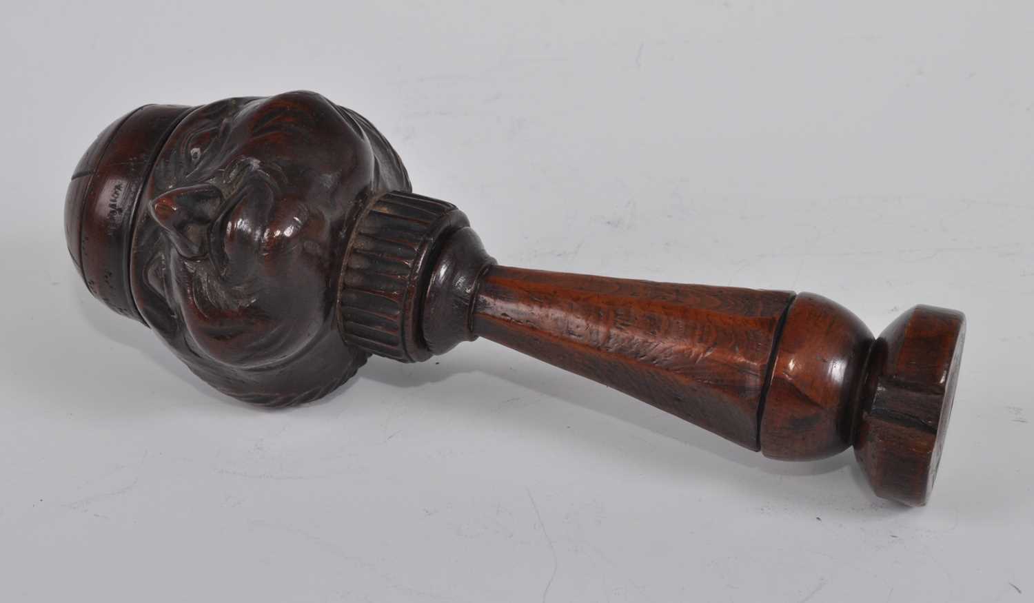 A 19th century treen figurative nutcracker, the head as a smiling man wearing a cap, the tapered