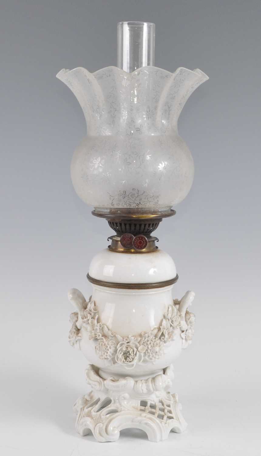 A 19th century blanc de chine porcelain oil lamp, the acid etched shade above a floral encrusted