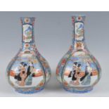 A pair of Japanese Meiji period Arita porcelain bottle vases, each enamel decorated with panels of