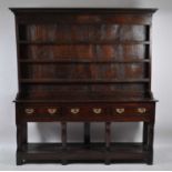A George III joined oak dresser, having three-tier plate rack over with dentil moulded cornice,