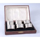 A cased set of six George V silver napkin rings, each of engine turned banded oval form with a