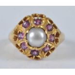 A yellow metal, pearl and ruby heavy circular cluster ring, featuring a centre 7.3mm cultured