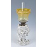 A 19th century Sitzendorf blanc de chine porcelain oil lamp, the acid etched amber tinted glass