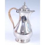 A George VI silver hot water pot, of plain baluster form with rattan covered handle, makers mark