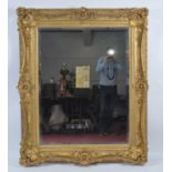 A Victorian giltwood and composition picture frame housing a later bevelled mirrorplate, the swept