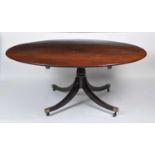 A late Georgian mahogany pedestal dining table, the oval tilt-top with boxwood stringing to a gun