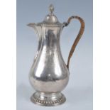 A George III silver hot water pot, of baluster form with gadrooned rims and flame finial, crest