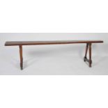 A 19th century fruitwood bench, the narrow one-piece top on ring turned triform end supports, w.