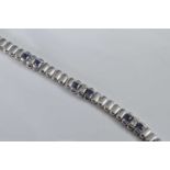 A white metal sapphire line bracelet, featuring eight sections with two blue and one colourless