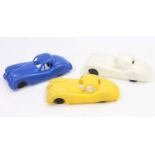 Three identical plastic moulded models of Jaguar XK120, one finished in yellow, one in white, and