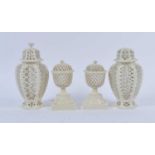 A pair of creamware urns, each having pierced decoration and mounted upon a square plinth, h.18cm;