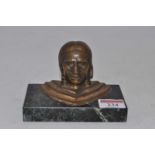 A bronzed paperweight in the form of a head and shoulders bust of a Native American, mounted upon