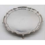 An Elizabeth II silver waiter, having pie-crust rim and standing upon four scrolled feet,