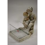 A modern plaster figurine with standing glass dish