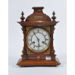 An early 20th century walnut cased eight-day mantel clock, the enamel dial showing Roman numerals,