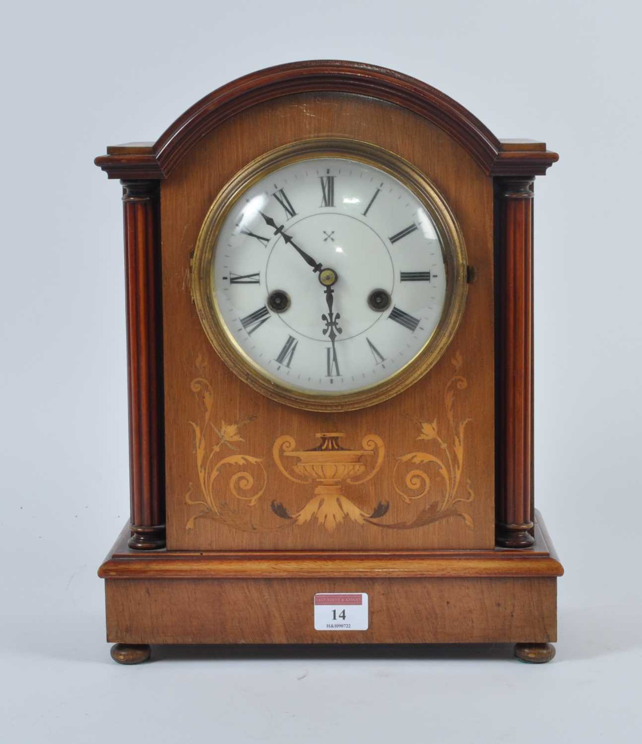 An early 20th century walnut cased eight-day mantel clock, the enamel dial showing Roman numerals,