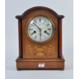An early 20th century walnut cased eight-day mantel clock, the enamel dial showing Roman numerals,