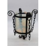 An Arts & Crafts style wrought iron framed ceiling light pendant having a cylindrical vaseline glass