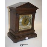 A circa 1900 oak cased mantel clock, of architectural form, the silvered dial showing Roman