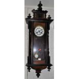 An early 20th century walnut and ebonised Vienna drop trunk wall clock, having pendulum and