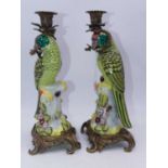 A pair of modern reproduction continental porcelain candlesticks each in the form of a parrot on a
