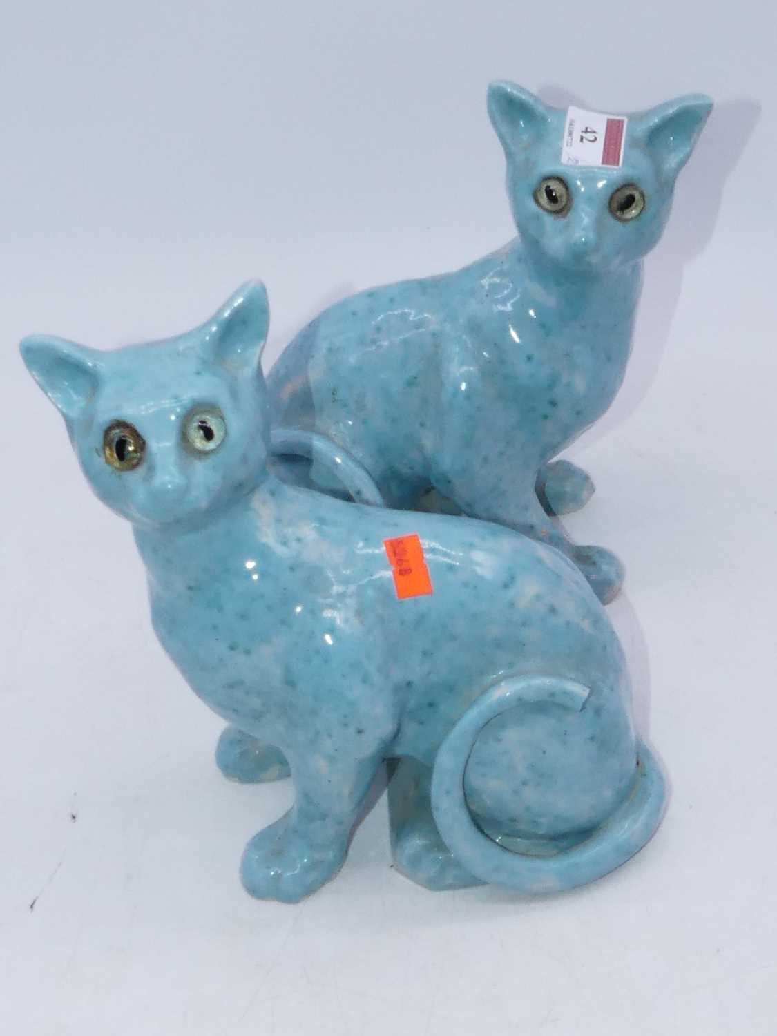 A pair of Galle style cats, each modelled in seated pose on a turquoise ground with glass eyes,