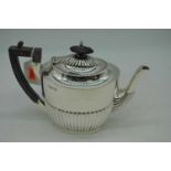 An Edward VII silver teapot of half-reeded form having ebonised finial and handle, Sheffield 1902,