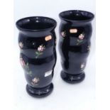 A pair of Victorian vases each of wavy tapering form on a black ground handpainted with flowers,