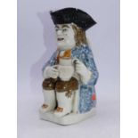 An 18th century pearlware toby jug in typical seated pose in sponged blue jacket, brown breeches and