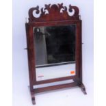 A George III style mahogany swing frame toiletry mirror, having a fret carved pediment above a