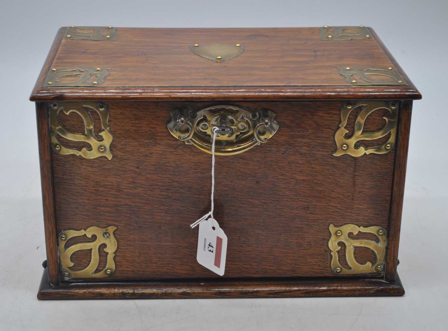 An early 20th century brass mounted oak stationery cabinet, the fall lifting to reveal an