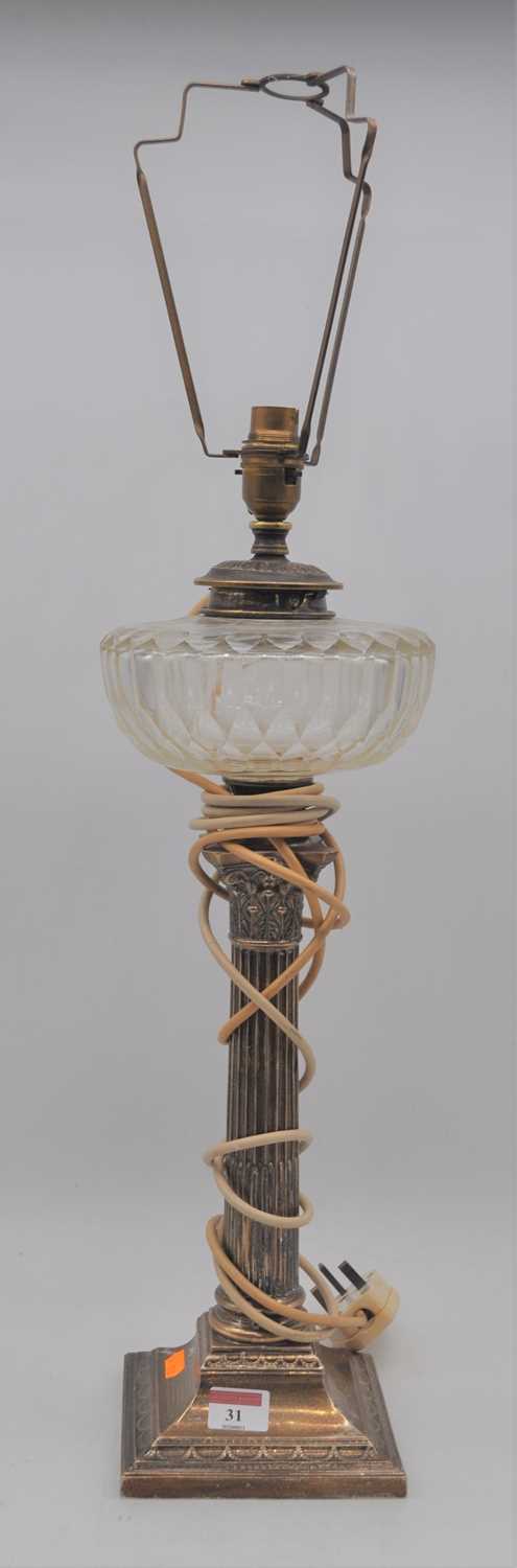 An Edwardian silver oil lamp having a cut clear glass font above a corinthian capital and fluted