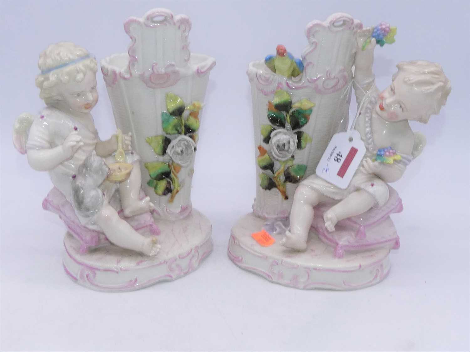 A pair of Victorian spill holders, each in the form of a child seated beside a basket surmounted