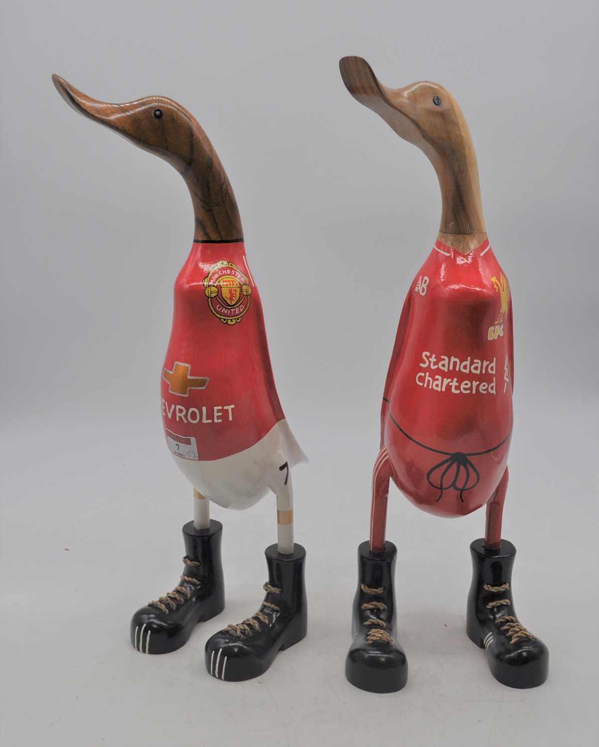 Two carved wooden model of ducks in football shirts