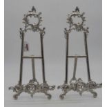A pair of reproduction Rococo-style white metal plated table easels, each with Rockdale