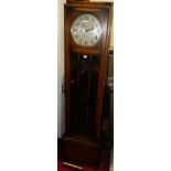 A 1930s oak long case clock by Enfield, having a glazed trunk door, silvered dial, pendulum with