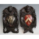 A pair of 18th century carved oak armorial plaques, carved with a cherub over leaf scrolls