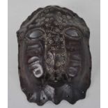 A turtle shell mask, carved with open eyes and mouth with circle and dot work inlaid decoration,