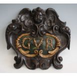 An 18th century carved oak armorial plaque, carved as a cherub mask over polychrome painted raised